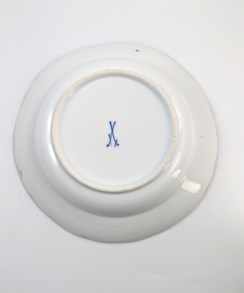 An antique white hard-paste porcelain plate decorated with hand-painted Kakiemon style motifs of a yellow tiger, purple bird, and flowering branches with a scalloped dark rim. View III