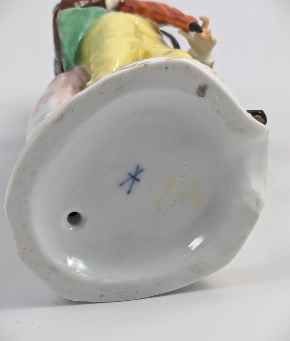 A 19th-century French Samson porcelain figurine depicting an umbrella seller in an 18th-century style tricorn hat, brown coat, and yellow breeches holding an orange umbrella. View VIII