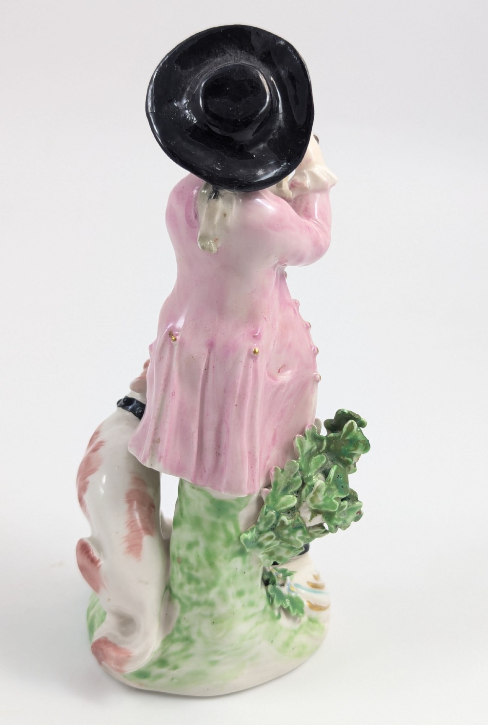 An 18th-century Derby soft-paste porcelain figurine depicting a shepherd playing a pipe with a dog standing beside him on a gilded scroll base. View V