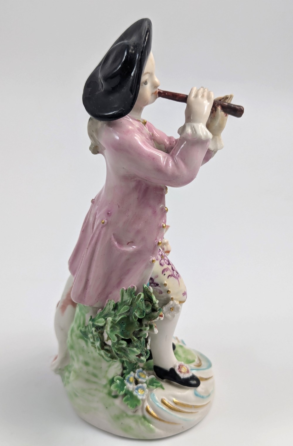 An 18th-century Derby soft-paste porcelain figurine depicting a shepherd playing a pipe with a dog standing beside him on a gilded scroll base. View VI