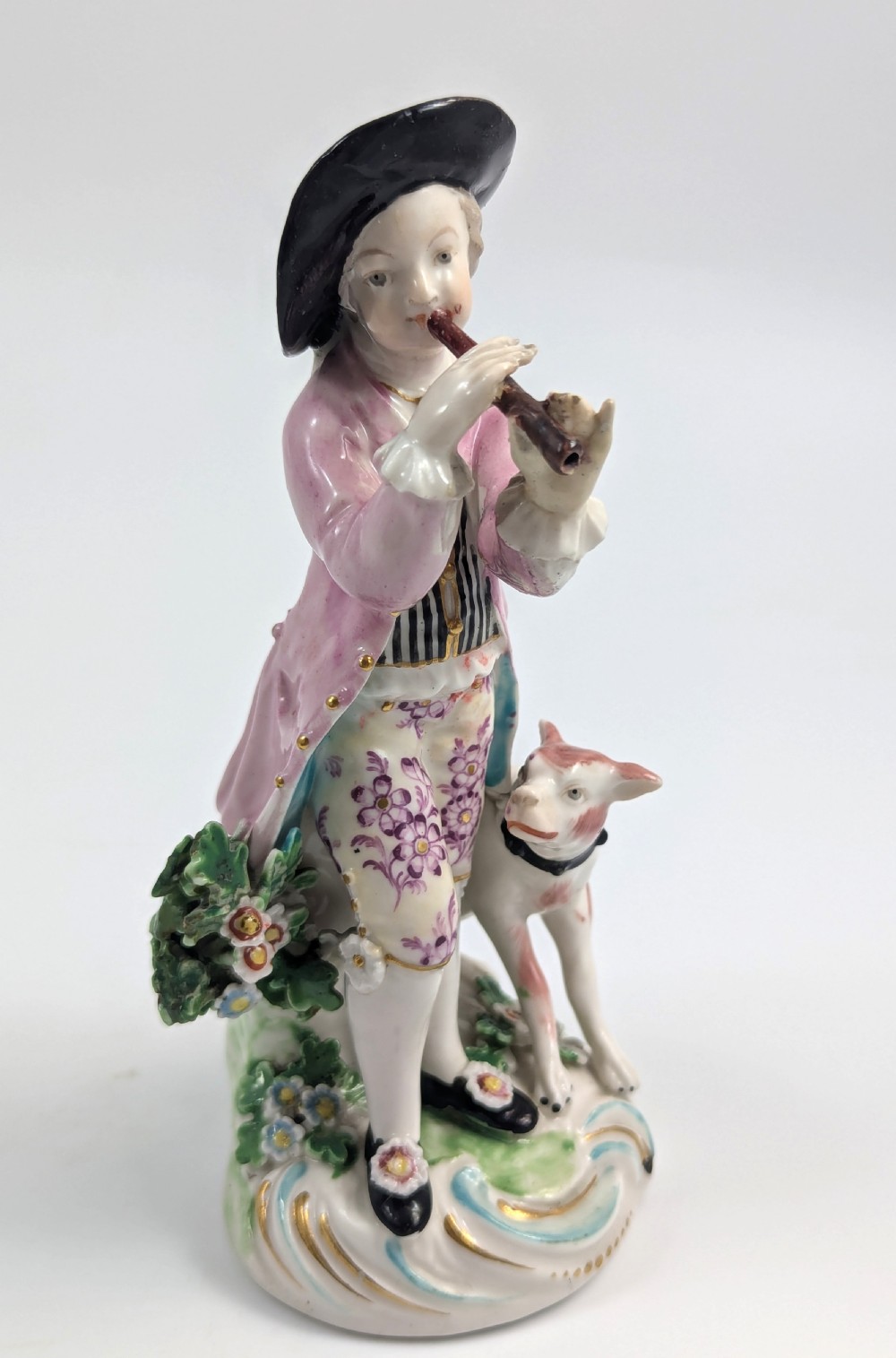 An 18th-century Derby soft-paste porcelain figurine depicting a shepherd playing a pipe with a dog standing beside him on a gilded scroll base. View VII