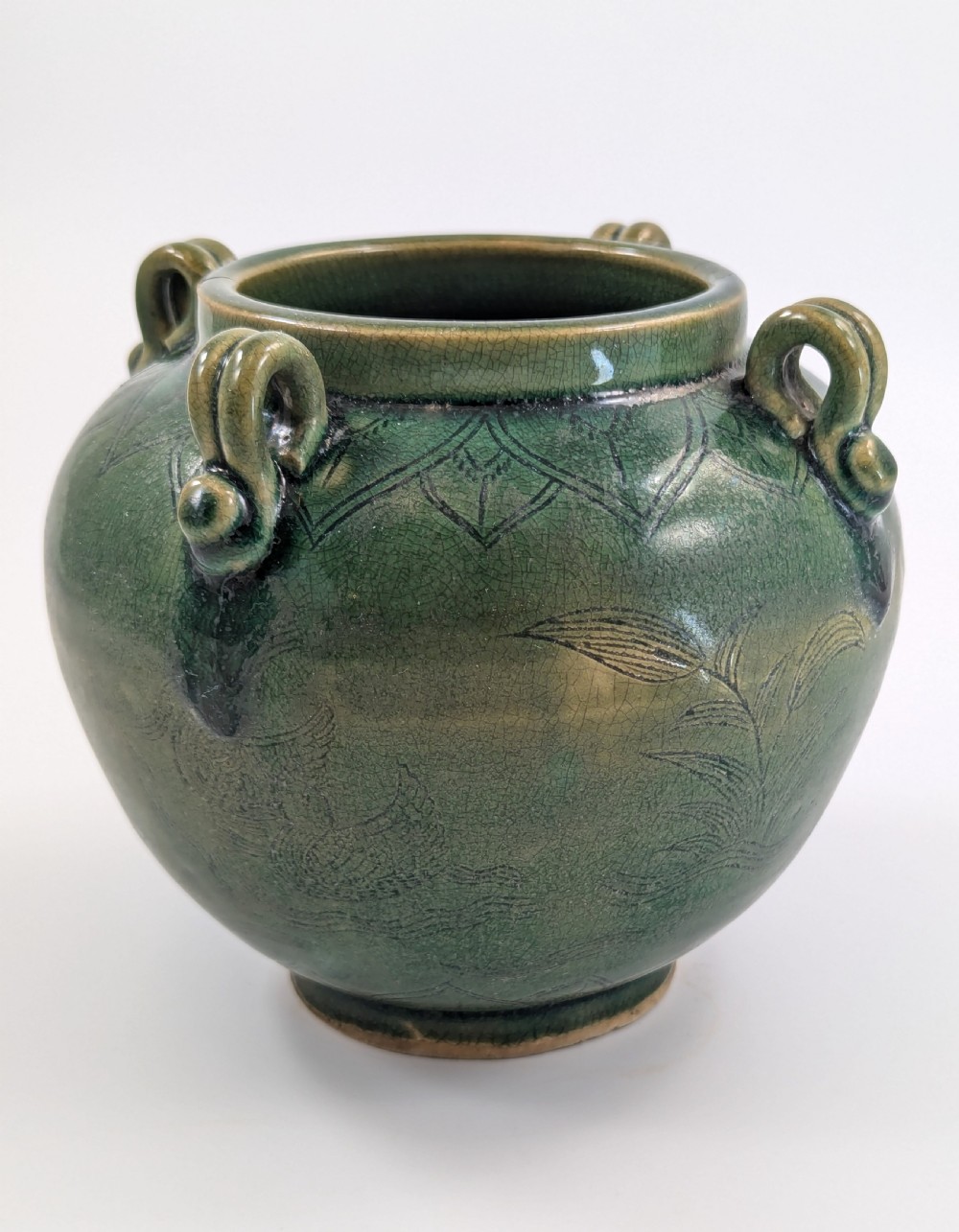 A rounded olive green celadon ceramic jar with four loop handles along the rim, featuring crackle glaze and incised line drawings of ducks and lotus plants. View III