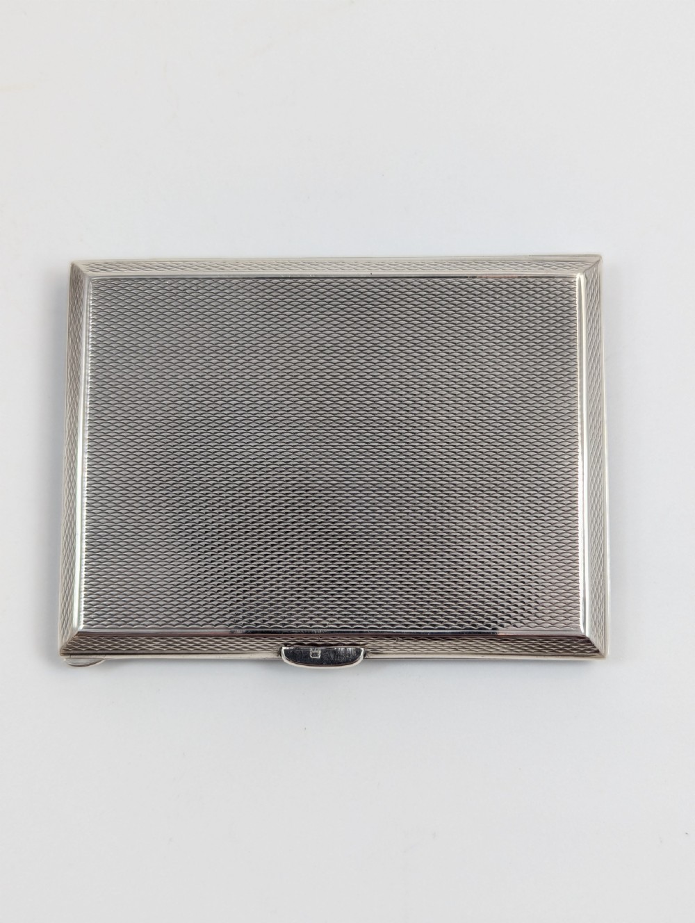 An Art Deco rectangular sterling silver cigarette case featuring a polished black enamel cover with a marcasite-inset rectangular corner detail and a beige suede pouch. View III
