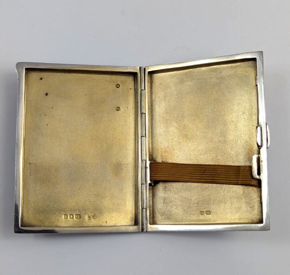 An Art Deco rectangular sterling silver cigarette case featuring a polished black enamel cover with a marcasite-inset rectangular corner detail and a beige suede pouch. View IV