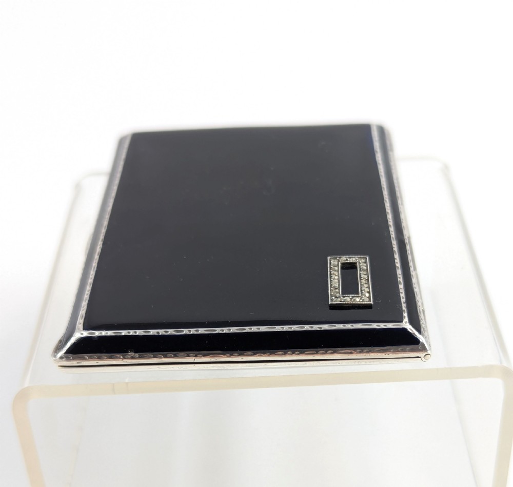 An Art Deco rectangular sterling silver cigarette case featuring a polished black enamel cover with a marcasite-inset rectangular corner detail and a beige suede pouch. View VIII