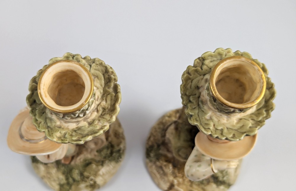 A pair of Victorian Royal Worcester porcelain candlesticks featuring a young boy and girl standing before tree trunk columns topped with leafy candle sconces. View VIII