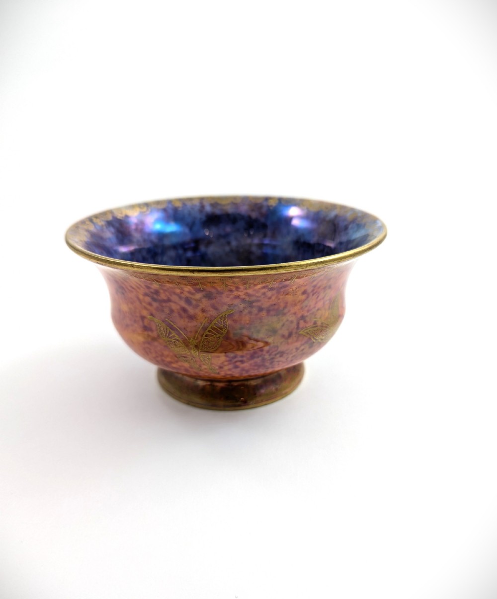 An antique Wedgwood ceramic bowl featuring a mottled orange and pink exterior with gilded butterfly motifs and an iridescent purple and blue interior glaze.