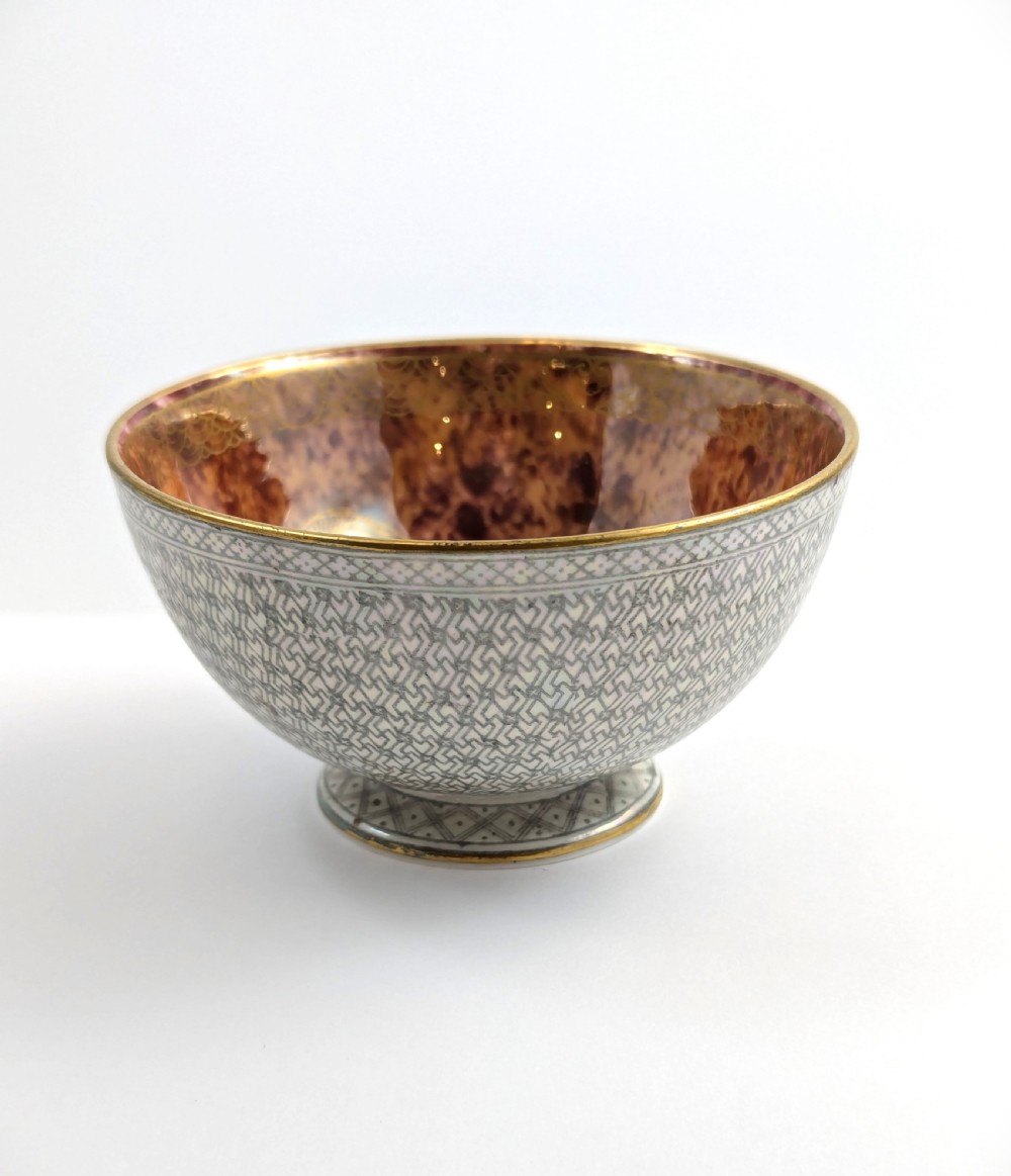 A small footed Wedgwood porcelain bowl featuring a grey diaper patterned exterior and a mottled orange lustre interior with gilt trim.