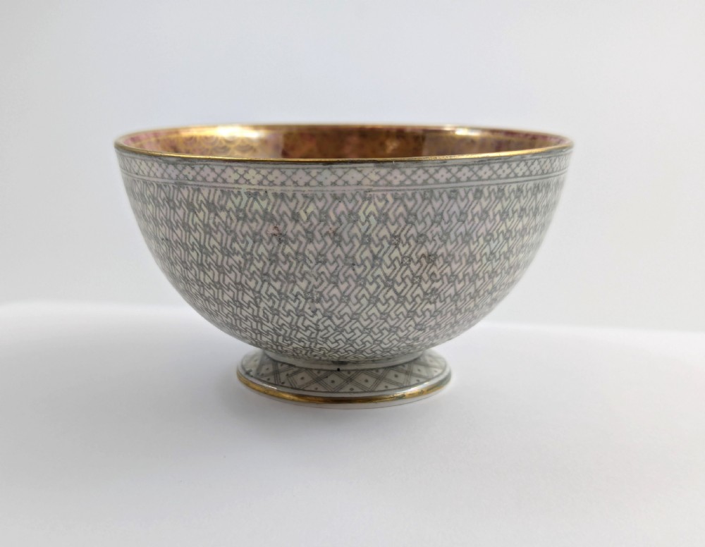 A small footed Wedgwood porcelain bowl featuring a grey diaper patterned exterior and a mottled orange lustre interior with gilt trim. View V