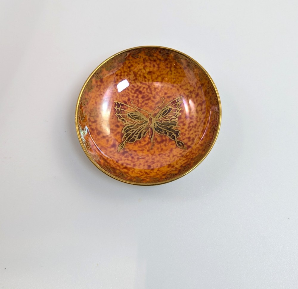 A small shallow ceramic bowl featuring a mottled orange iridescent lustre interior with gilt edging and a light pearlescent exterior. View III