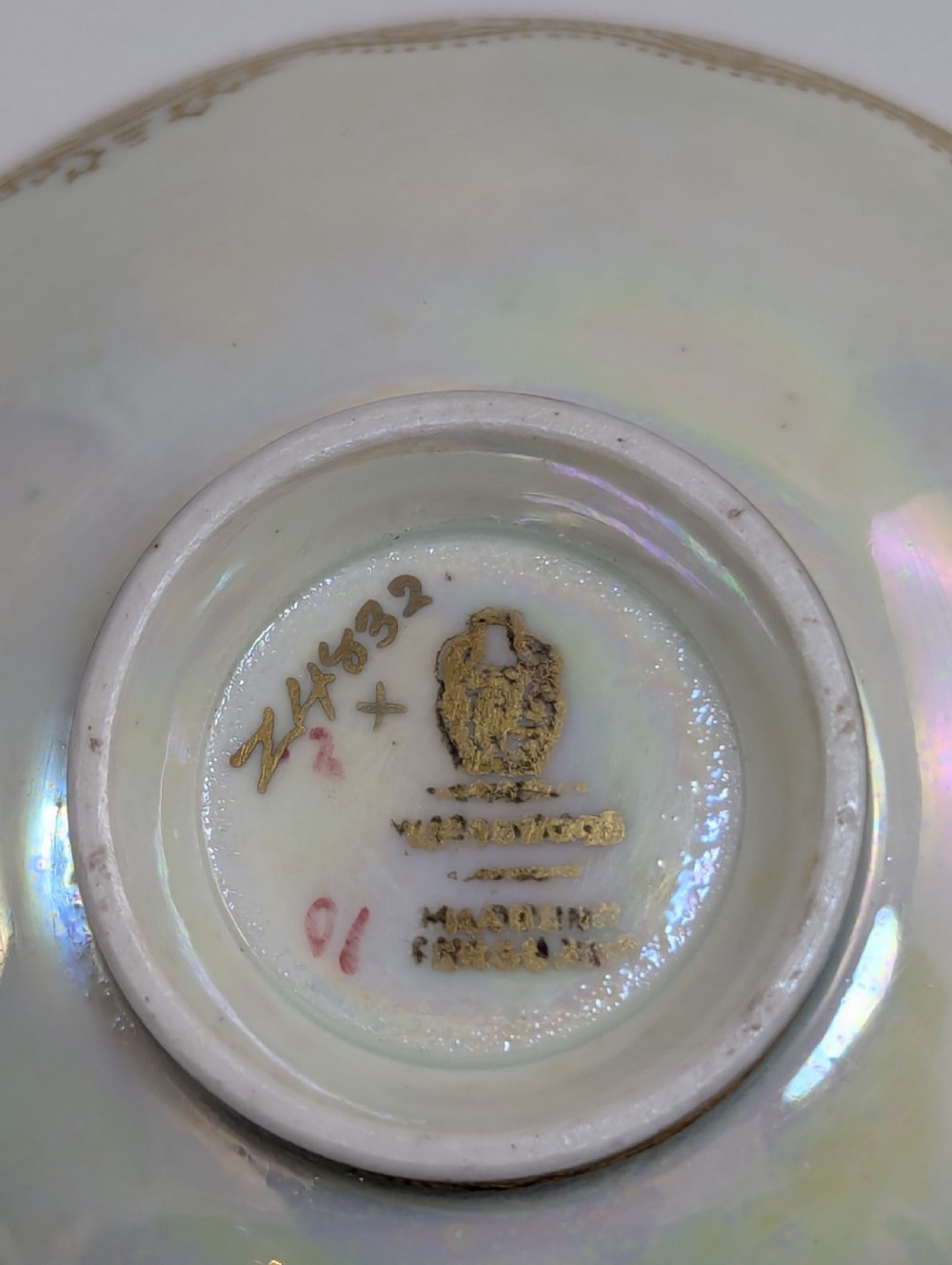 A small shallow ceramic bowl featuring a mottled orange iridescent lustre interior with gilt edging and a light pearlescent exterior. View VI