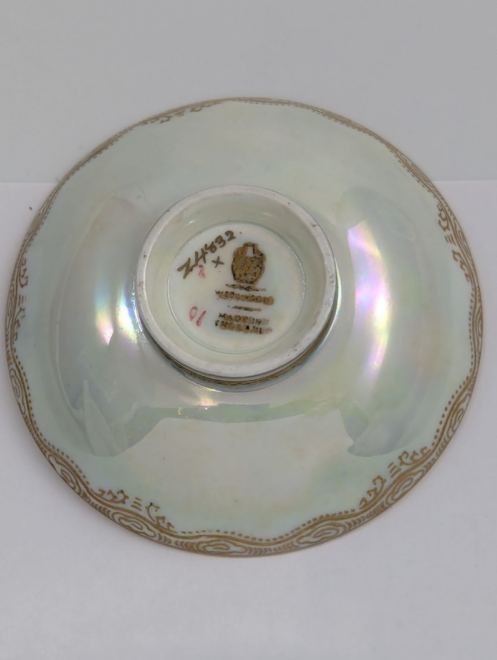 A small shallow ceramic bowl featuring a mottled orange iridescent lustre interior with gilt edging and a light pearlescent exterior. View VII