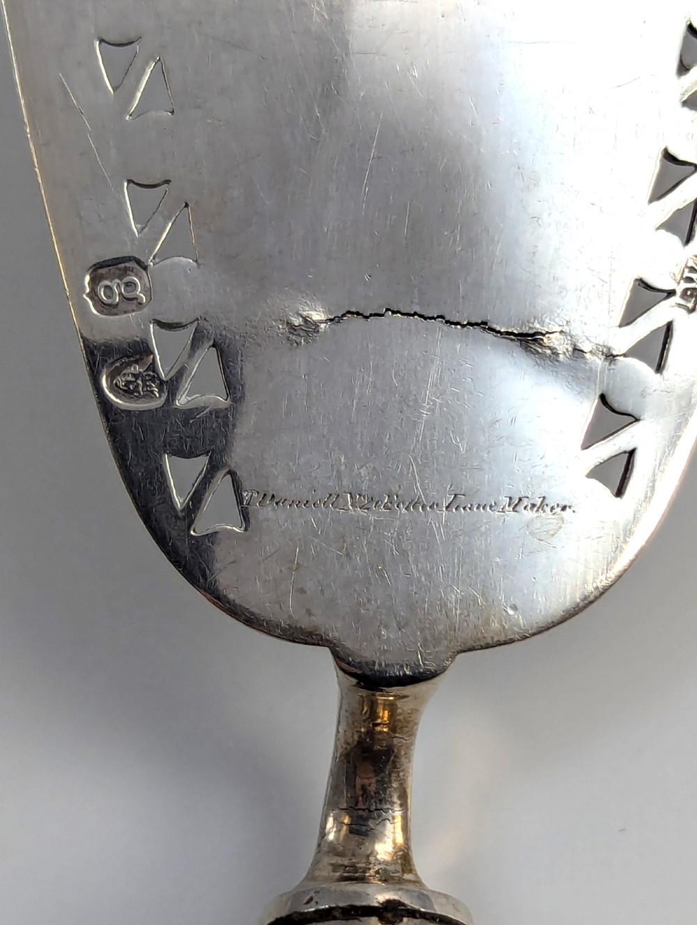 An antique George III sterling silver fish slice featuring an intricately pierced and engraved blade with a tapered handle. View III
