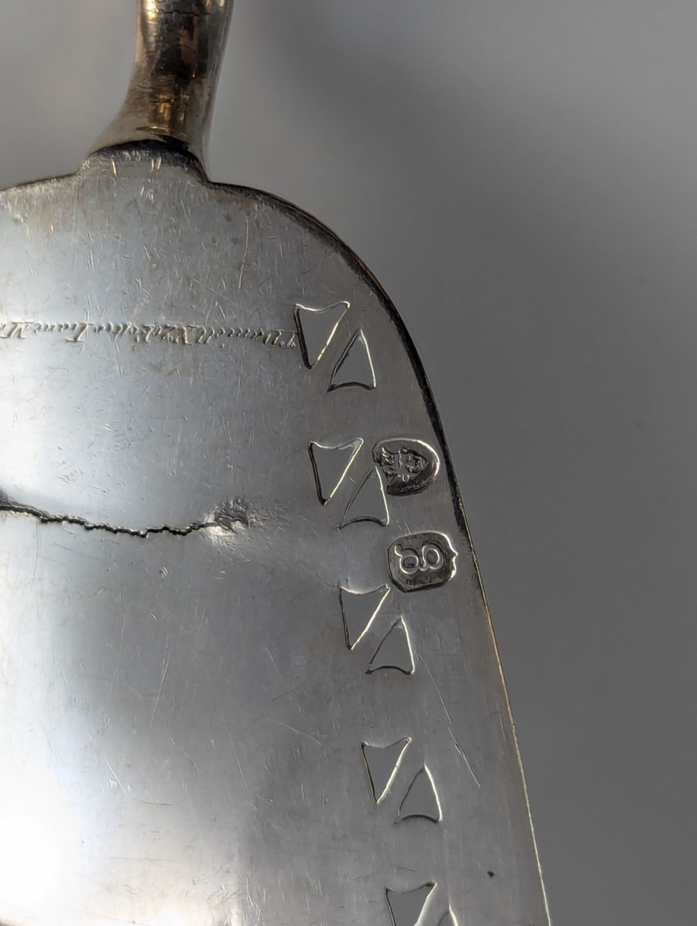 An antique George III sterling silver fish slice featuring an intricately pierced and engraved blade with a tapered handle. View V