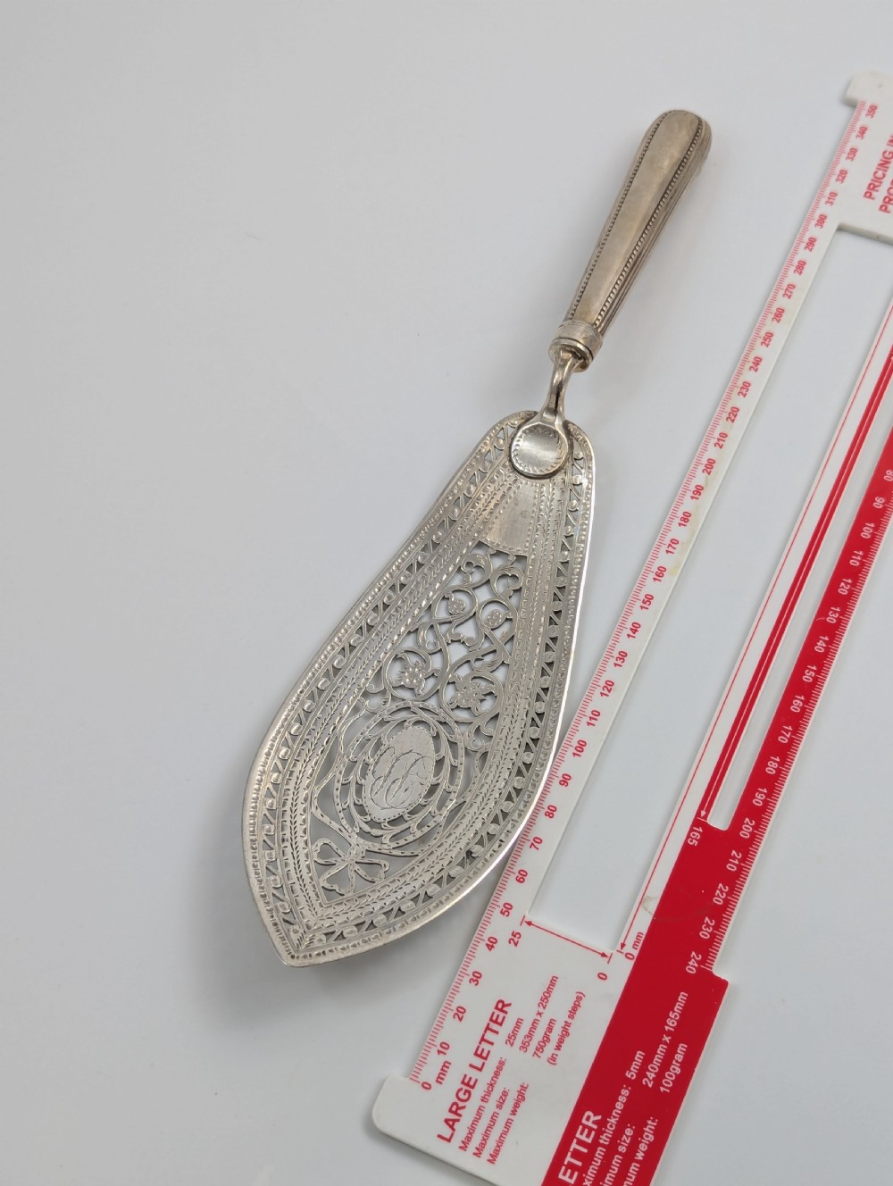 An antique George III sterling silver fish slice featuring an intricately pierced and engraved blade with a tapered handle. View IX