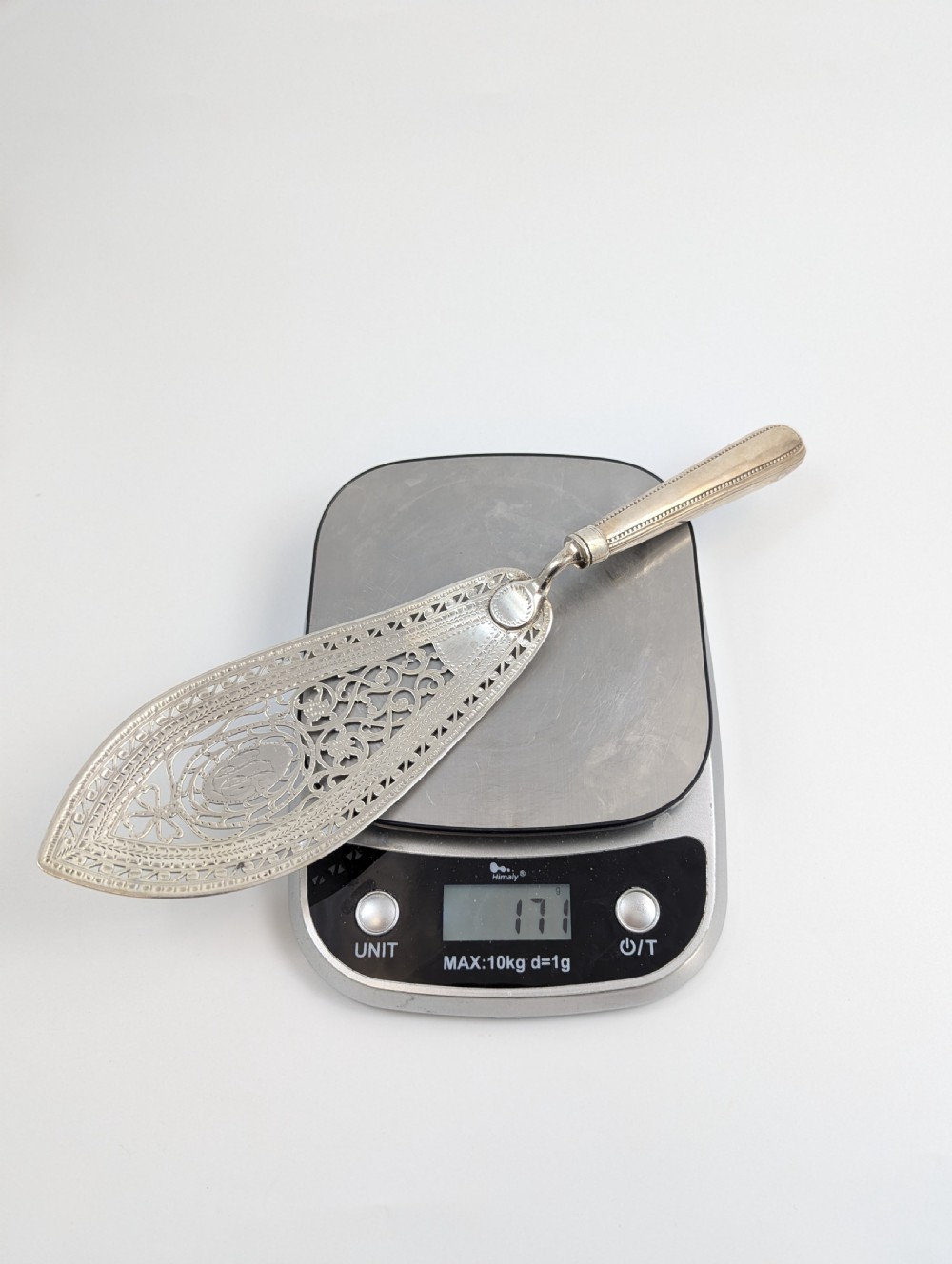 An antique George III sterling silver fish slice featuring an intricately pierced and engraved blade with a tapered handle. View X