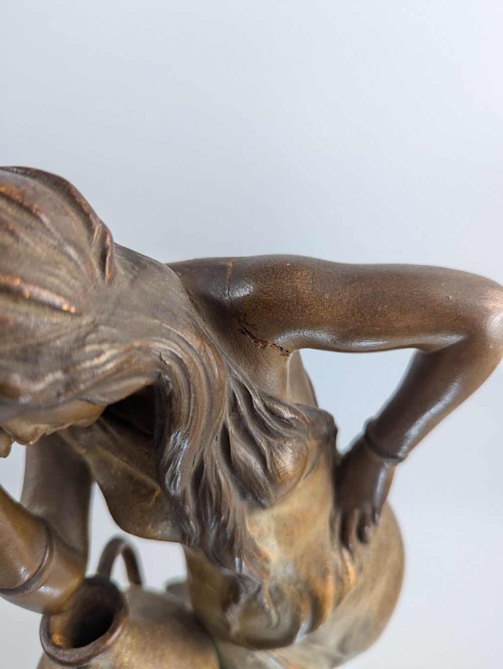 An Art Nouveau earthenware figurine depicting a draped female figure resting against a water pitcher on a stone-effect pillar. View XII