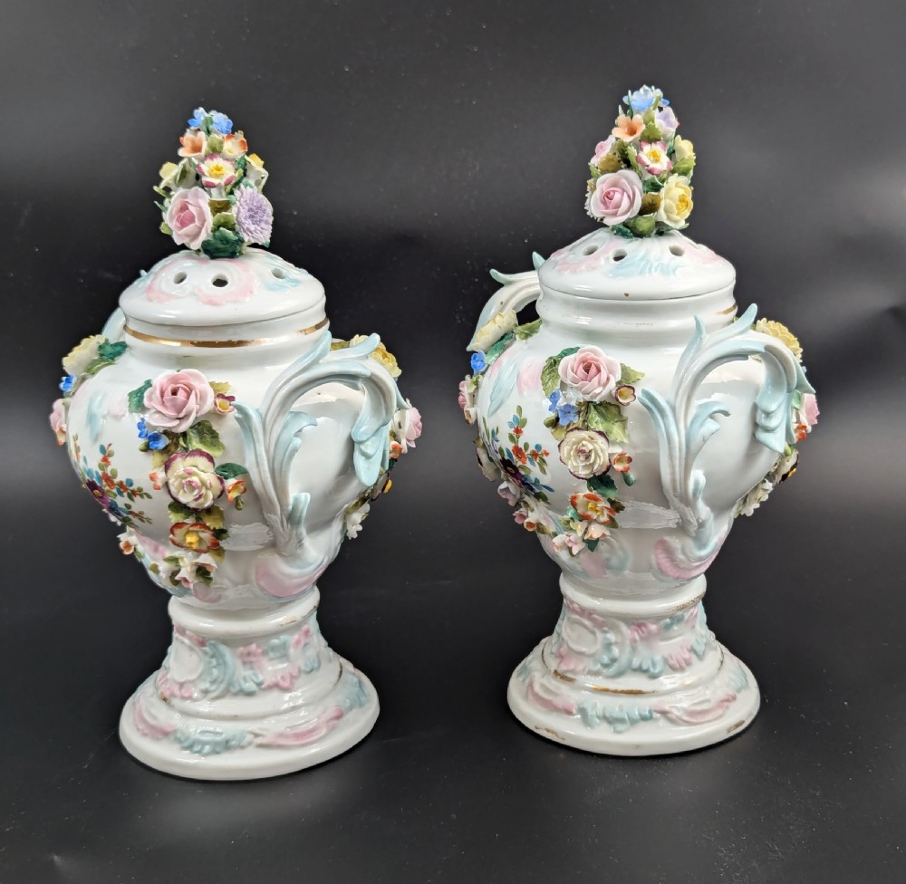A pair of antique Sitzendorf hard-paste white porcelain potpourri vases decorated with encrusted hand-moulded flowers, scrolling handles, pierced lids, and painted floral sprays. View II