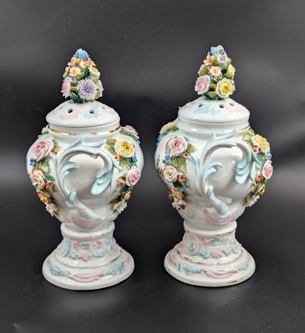 A pair of antique Sitzendorf hard-paste white porcelain potpourri vases decorated with encrusted hand-moulded flowers, scrolling handles, pierced lids, and painted floral sprays. View III
