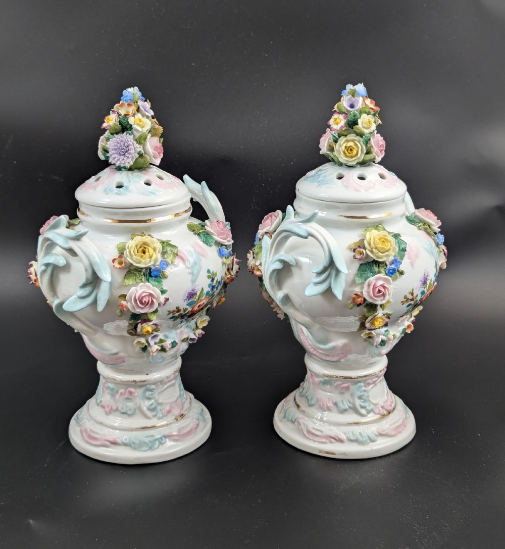 A pair of antique Sitzendorf hard-paste white porcelain potpourri vases decorated with encrusted hand-moulded flowers, scrolling handles, pierced lids, and painted floral sprays. View IV