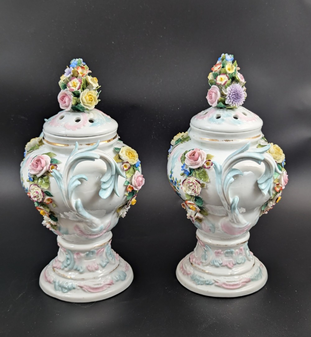 A pair of antique Sitzendorf hard-paste white porcelain potpourri vases decorated with encrusted hand-moulded flowers, scrolling handles, pierced lids, and painted floral sprays. View VII