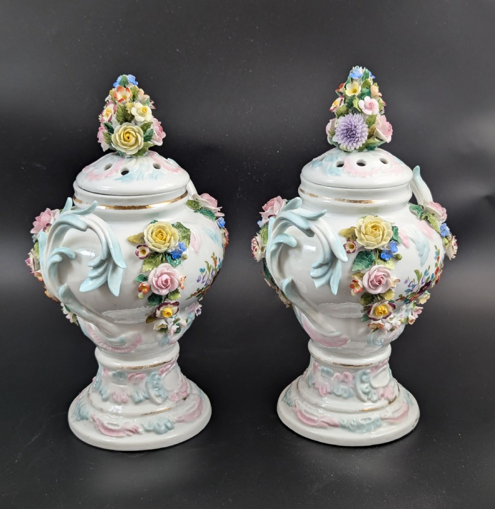 A pair of antique Sitzendorf hard-paste white porcelain potpourri vases decorated with encrusted hand-moulded flowers, scrolling handles, pierced lids, and painted floral sprays. View VIII