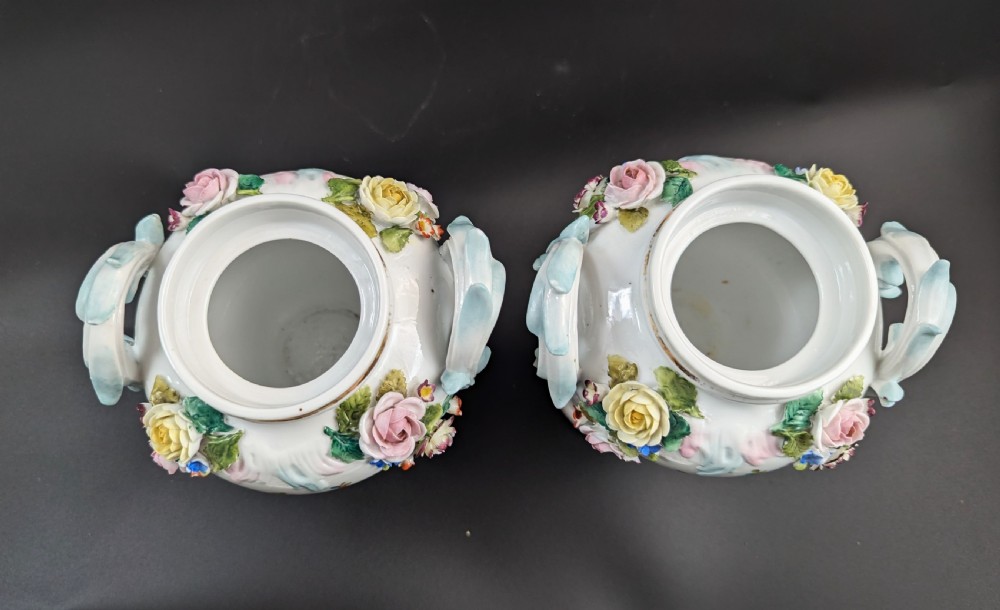 A pair of antique Sitzendorf hard-paste white porcelain potpourri vases decorated with encrusted hand-moulded flowers, scrolling handles, pierced lids, and painted floral sprays. View XI