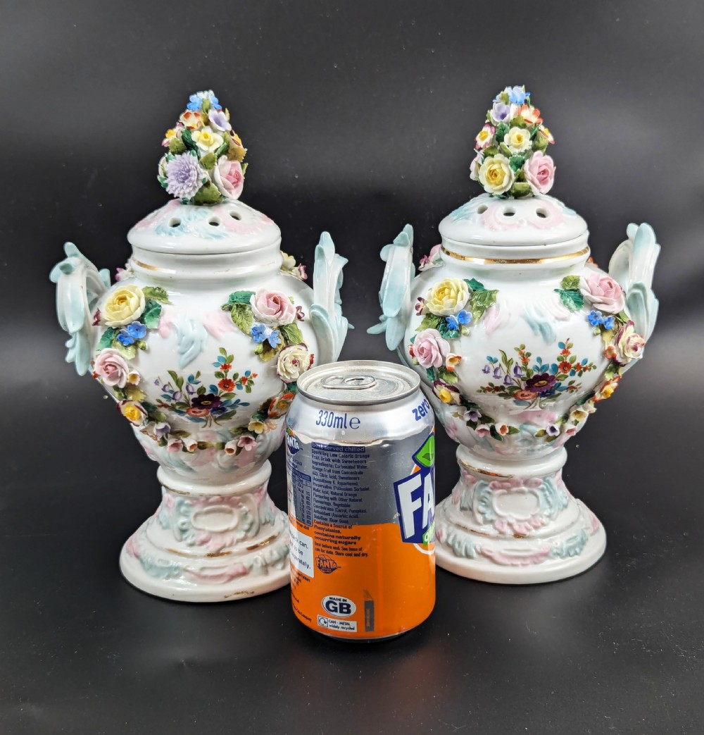 A pair of antique Sitzendorf hard-paste white porcelain potpourri vases decorated with encrusted hand-moulded flowers, scrolling handles, pierced lids, and painted floral sprays. View XVII