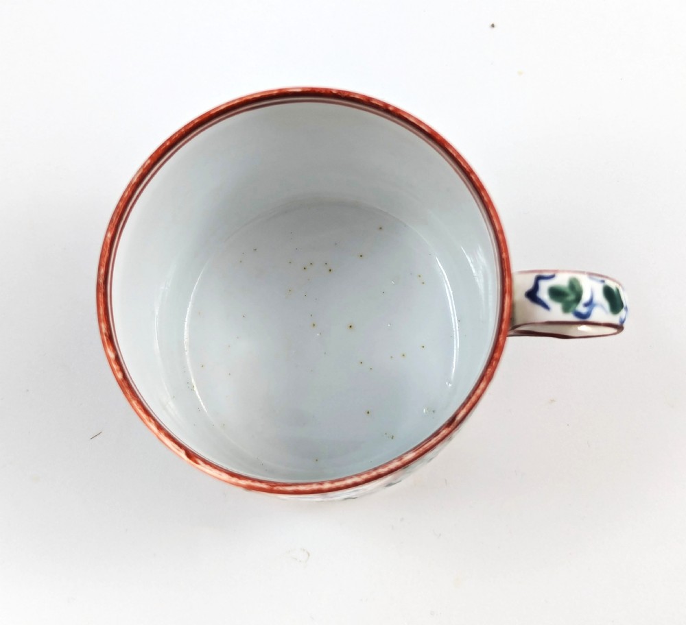 An early nineteenth-century Minton porcelain trio comprising a coffee can, saucer, and plate decorated with hand-painted terracotta, blue, and green floral and animal motifs. View XI