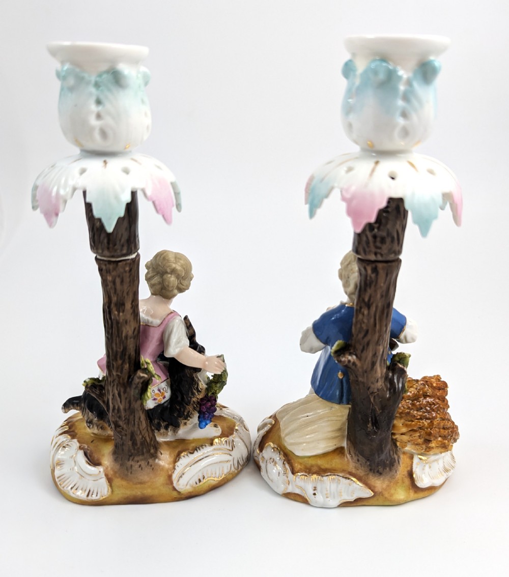 A pair of hand-painted German Sitzendorf porcelain figural candlesticks featuring a shepherdess and a lute player seated beside tree trunks supporting leafy sconces. View III