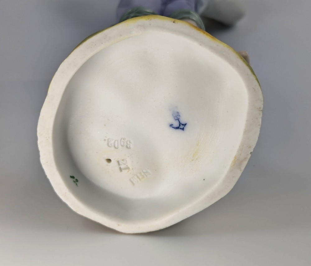 A pair of hand-painted German porcelain figurines depicting a boy and a girl carrying younger children piggyback style on tree stump bases. View VII