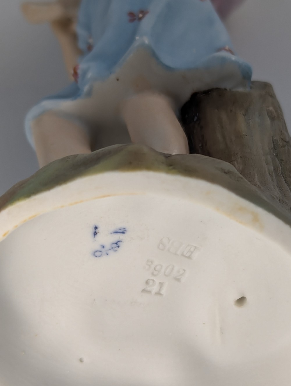 A pair of hand-painted German porcelain figurines depicting a boy and a girl carrying younger children piggyback style on tree stump bases. View VIII
