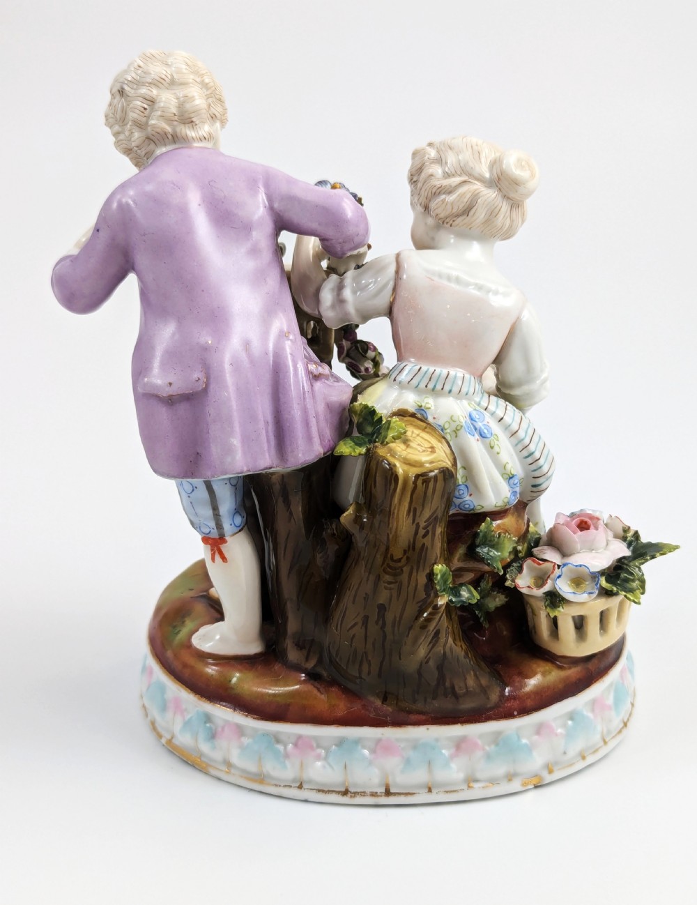 A nineteenth-century Meissen-style hand-painted porcelain figural group depicting two children with floral garlands beside a birdcage on a circular moulded base. View IV