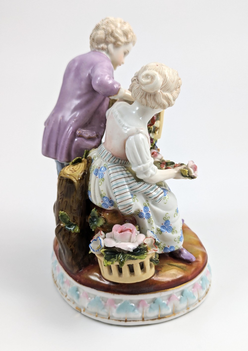 A nineteenth-century Meissen-style hand-painted porcelain figural group depicting two children with floral garlands beside a birdcage on a circular moulded base. View V