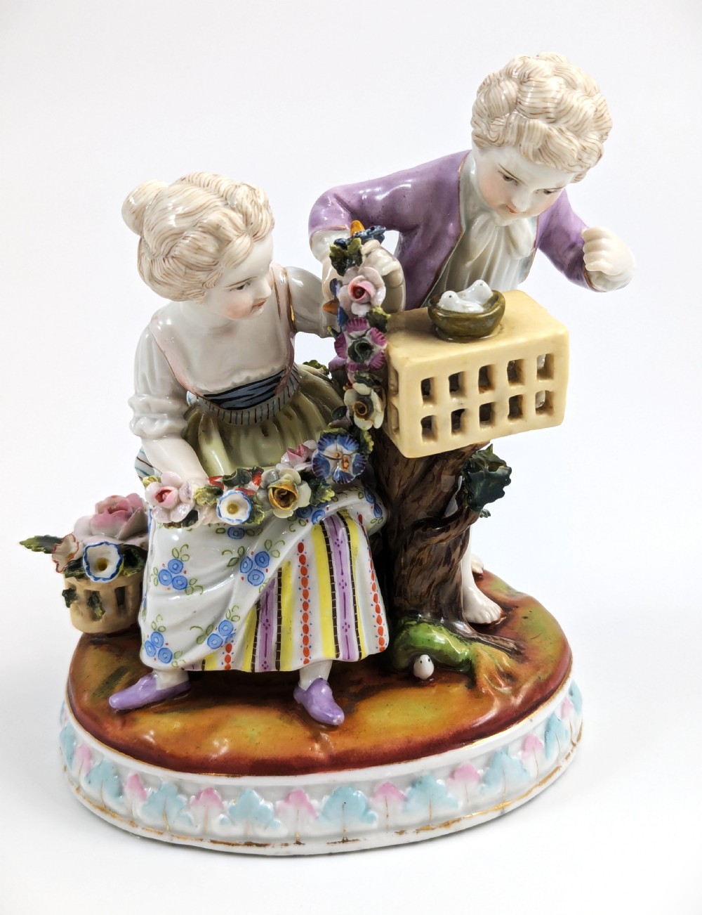 A nineteenth-century Meissen-style hand-painted porcelain figural group depicting two children with floral garlands beside a birdcage on a circular moulded base. View VII