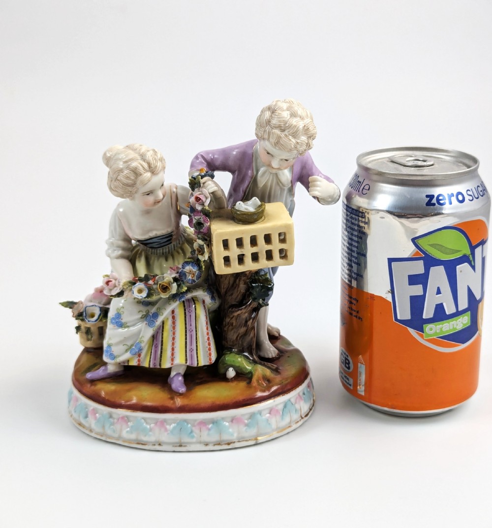 A nineteenth-century Meissen-style hand-painted porcelain figural group depicting two children with floral garlands beside a birdcage on a circular moulded base. View VIII