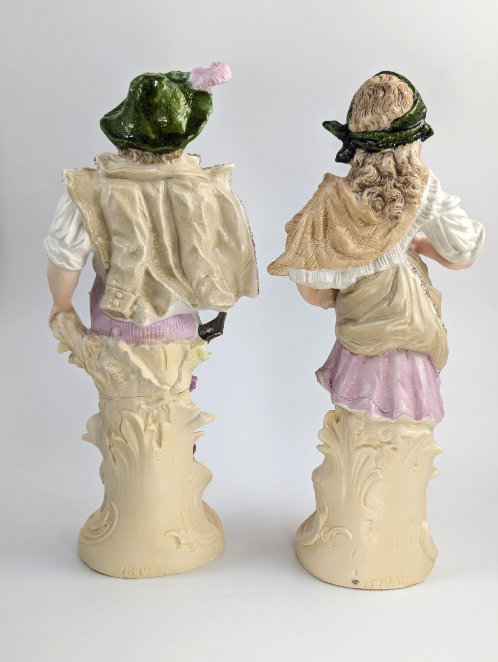A pair of antique German bisque porcelain figurines depicting a man and woman in detailed pastoral attire with gilded accents on scroll bases. View III
