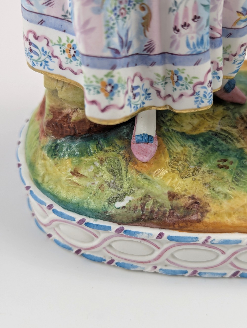 A 19th-century French bisque porcelain figural vase featuring a female figure in pastel Rococo costume standing beside a lattice-patterned vase on a painted base. View XI