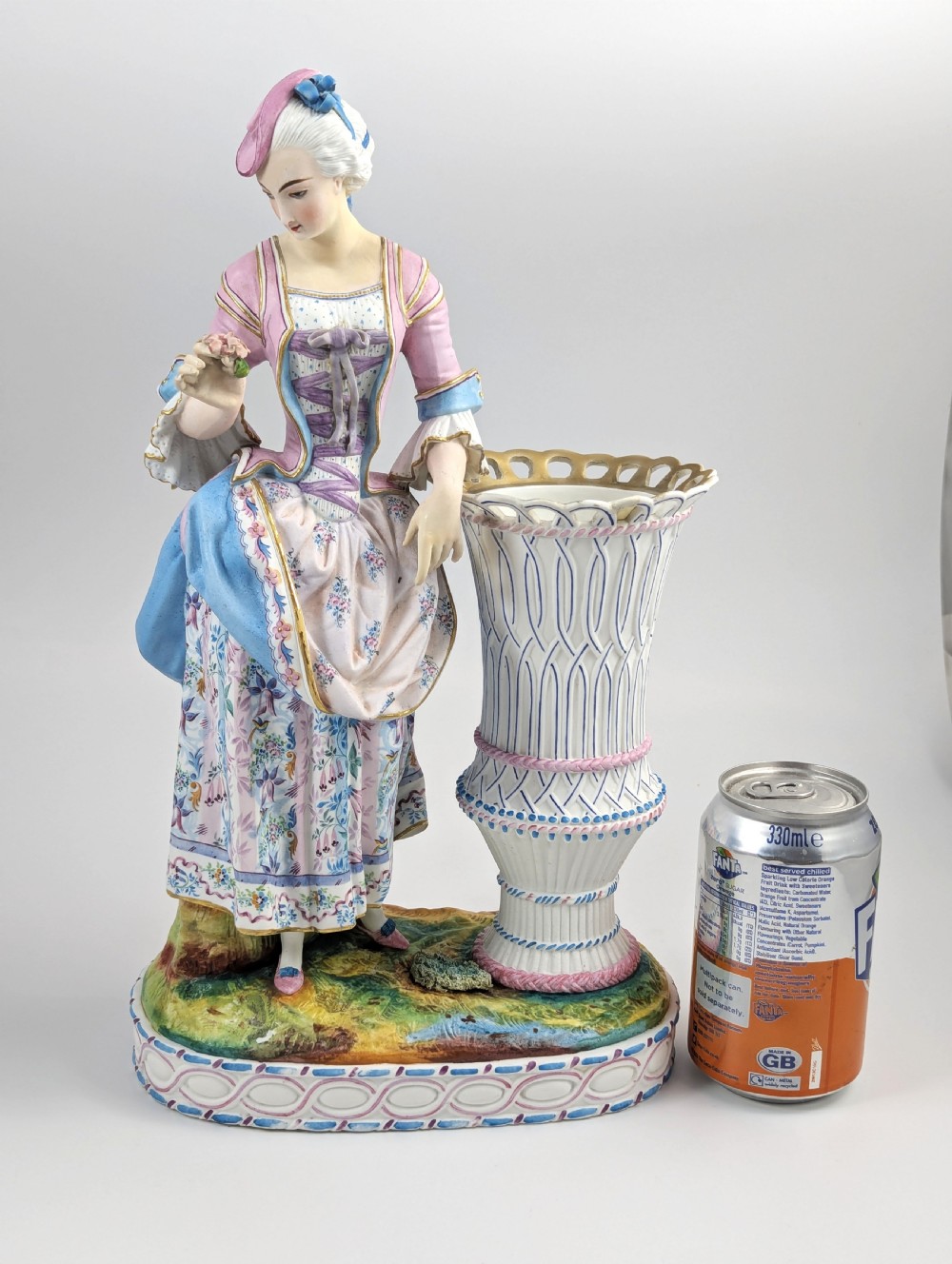 A 19th-century French bisque porcelain figural vase featuring a female figure in pastel Rococo costume standing beside a lattice-patterned vase on a painted base. View XIII