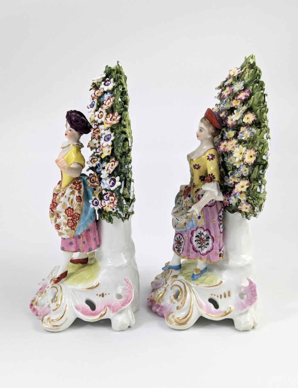 A pair of 19th-century Samson of Paris hand-painted porcelain figures standing against dense, flowering green bocage backgrounds on scrollwork bases. View II