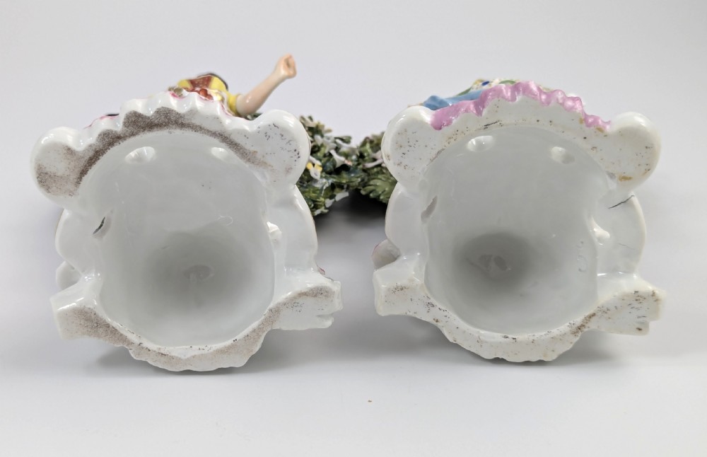 A pair of 19th-century Samson of Paris hand-painted porcelain figures standing against dense, flowering green bocage backgrounds on scrollwork bases. View V