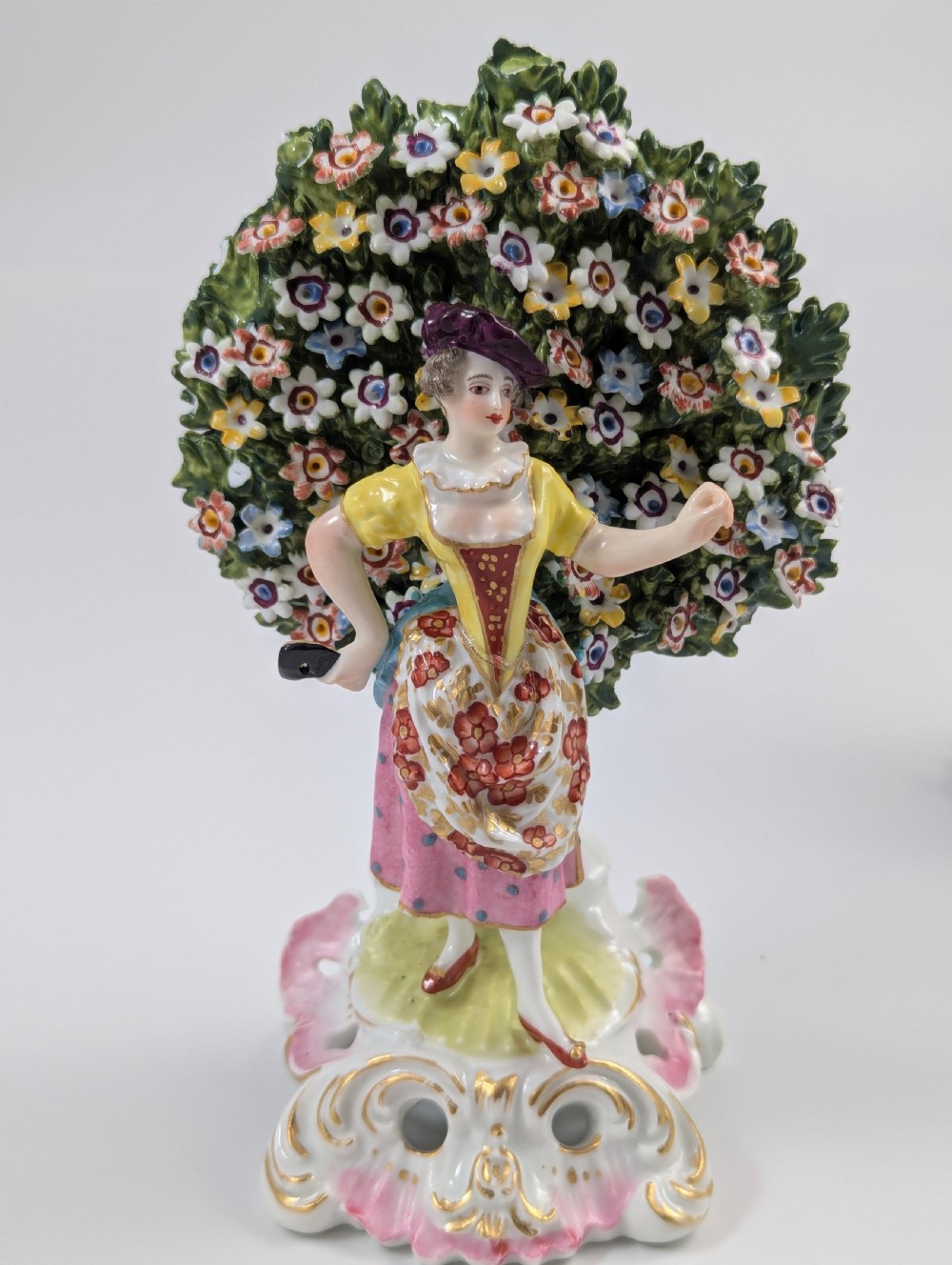A pair of 19th-century Samson of Paris hand-painted porcelain figures standing against dense, flowering green bocage backgrounds on scrollwork bases. View VI