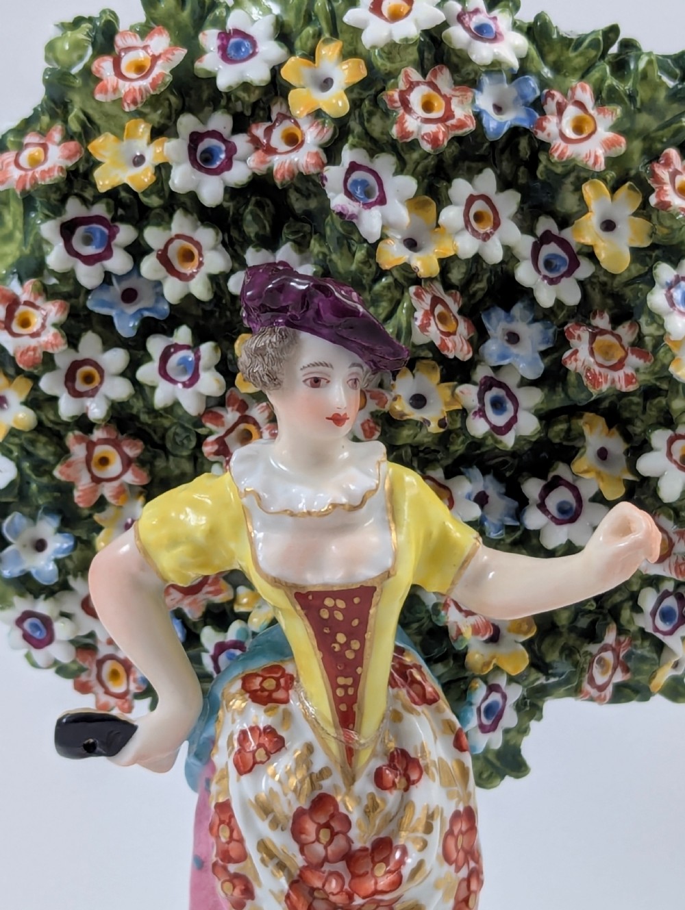 A pair of 19th-century Samson of Paris hand-painted porcelain figures standing against dense, flowering green bocage backgrounds on scrollwork bases. View VII
