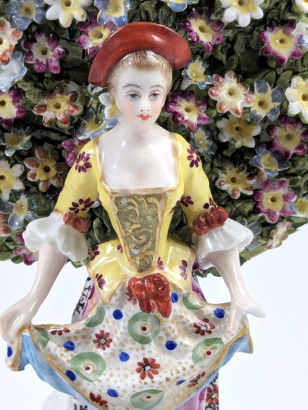 A pair of 19th-century Samson of Paris hand-painted porcelain figures standing against dense, flowering green bocage backgrounds on scrollwork bases. View IX