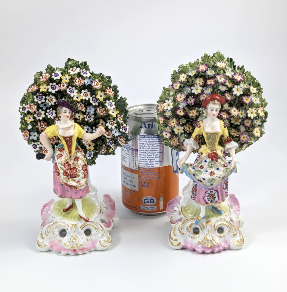 A pair of 19th-century Samson of Paris hand-painted porcelain figures standing against dense, flowering green bocage backgrounds on scrollwork bases. View XI