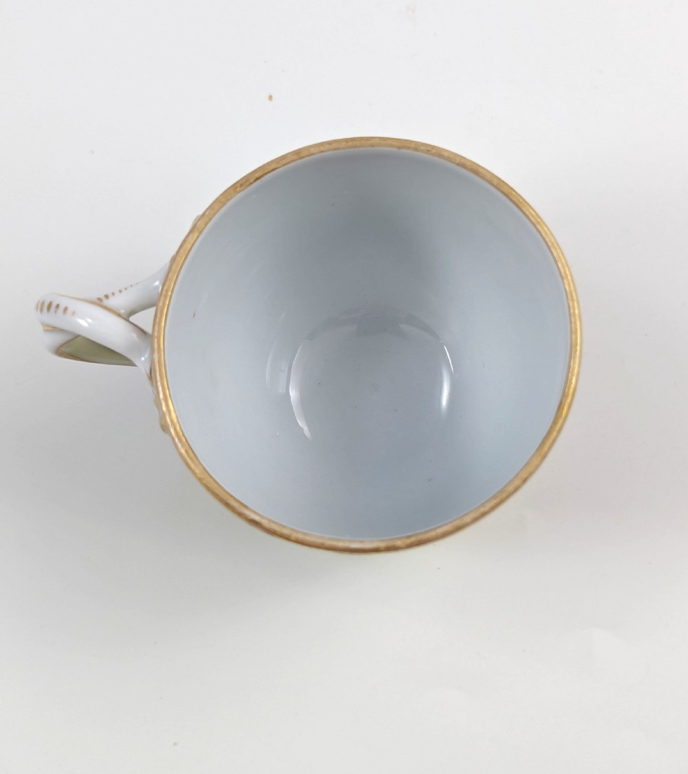 An antique nineteenth-century Meissen porcelain demitasse cup and saucer in yellow featuring hand-painted pastoral scenes set within intricate gilded cartouches. View IX