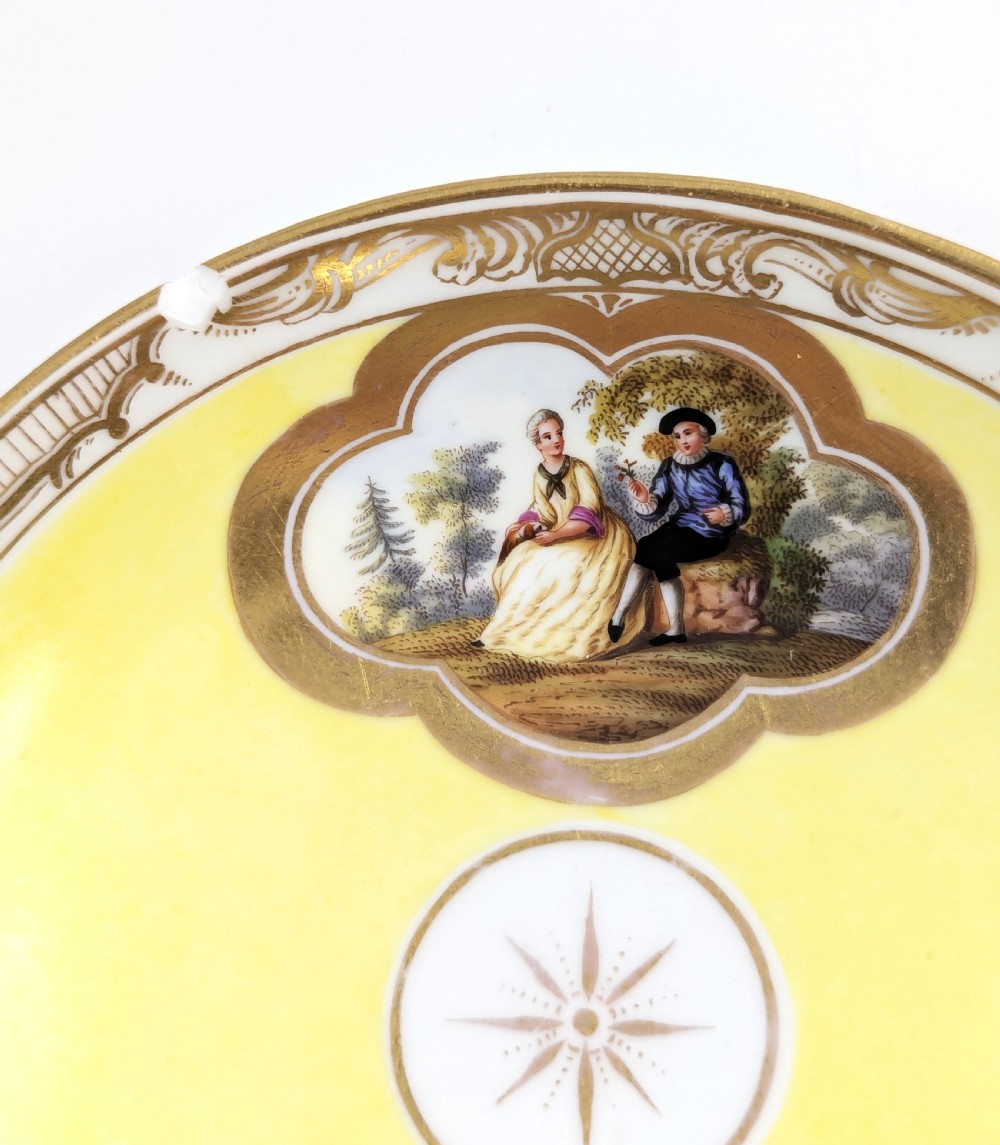 An antique nineteenth-century Meissen porcelain demitasse cup and saucer in yellow featuring hand-painted pastoral scenes set within intricate gilded cartouches. View XIII