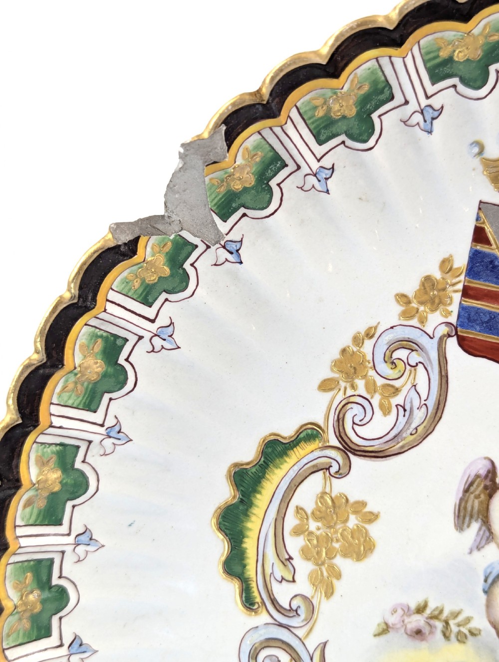 A pair of 18th-century French tin-glazed earthenware display plates with hand-painted putti motifs, armorial shields, and green scalloped borders. View III