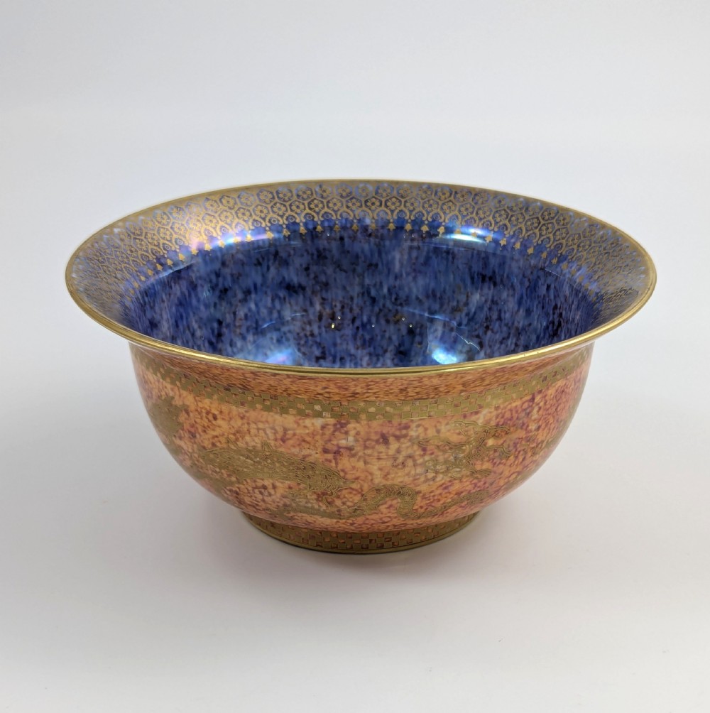 A circular ceramic bowl displaying a mottled orange and gold exterior with a deep speckled blue interior bordered by detailed gilt geometric patterns. View II