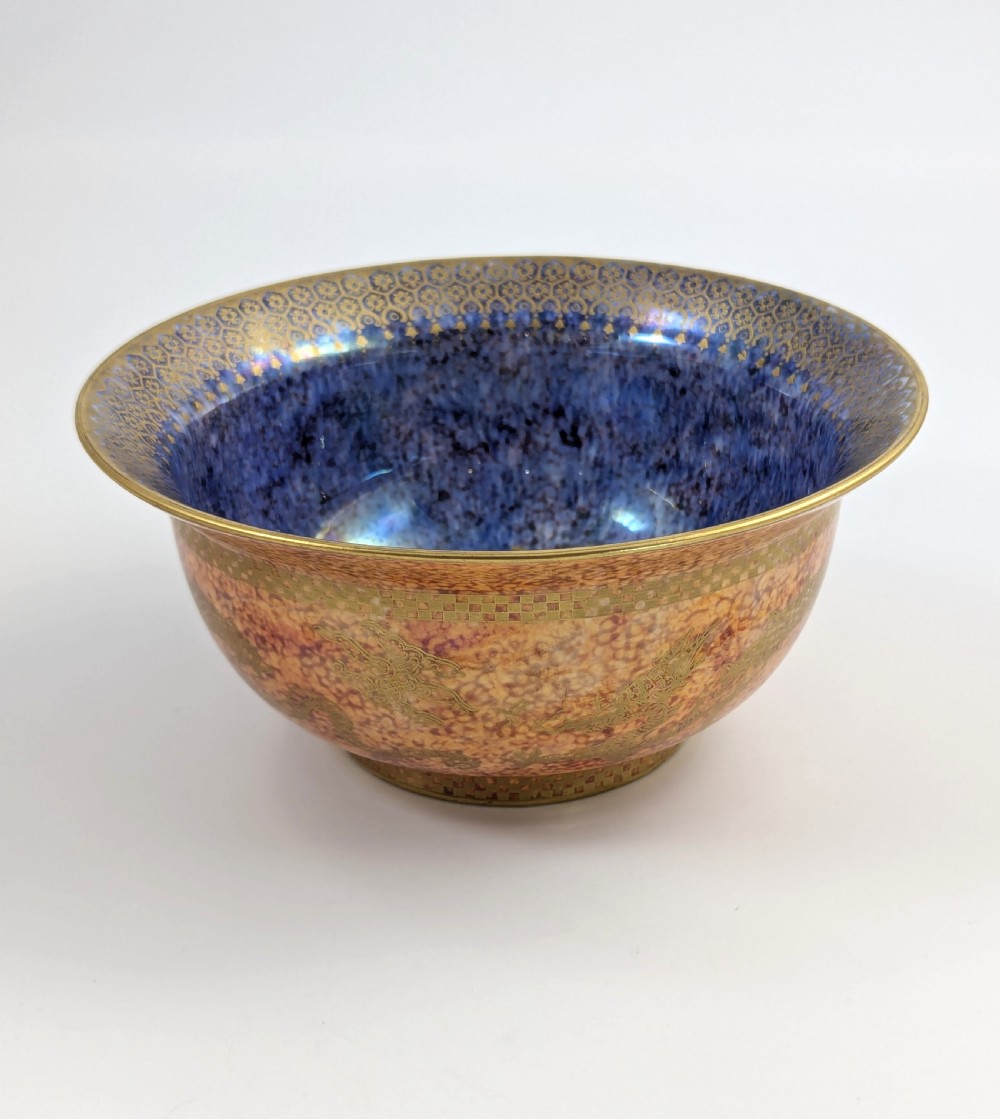 A circular ceramic bowl displaying a mottled orange and gold exterior with a deep speckled blue interior bordered by detailed gilt geometric patterns. View IV